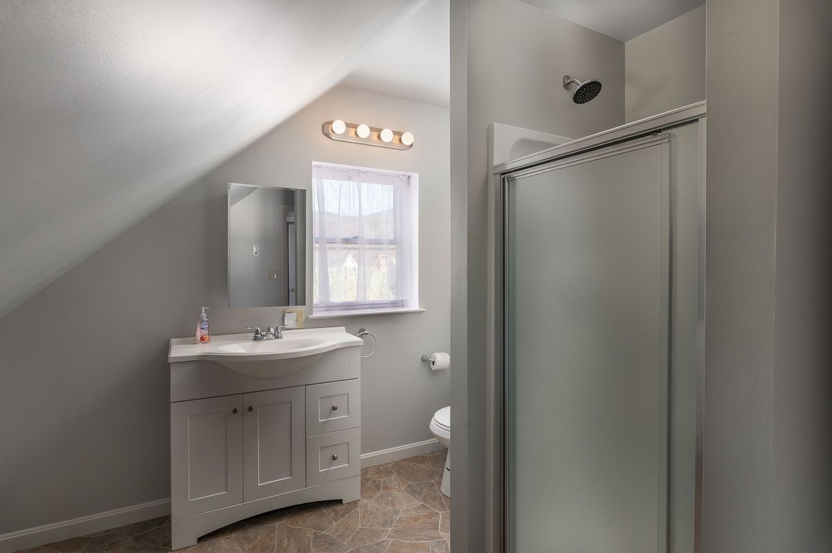 A clean and modern bathroom with a white vanity, mirror, and shower.