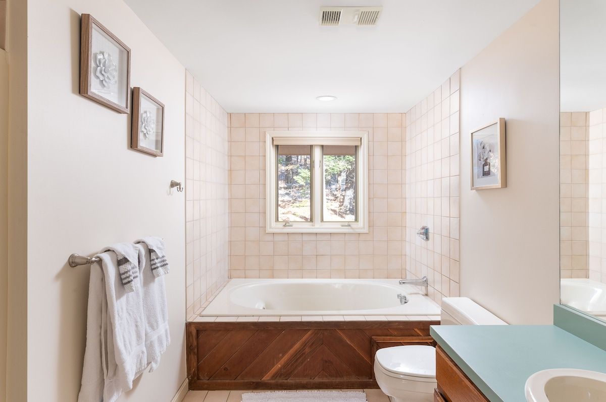 A clean and well-lit bathroom with a white bathtub, toilet, and vanity.
