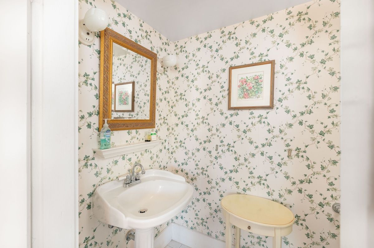 A small bathroom with a white sink and floral wallpaper.