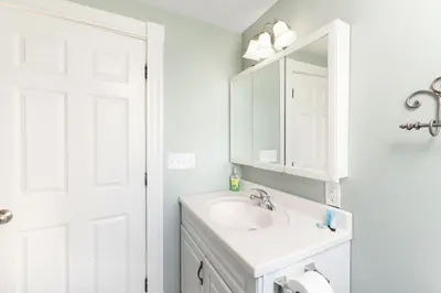 A clean and well-lit bathroom with a white vanity, mirror, and light fixture.