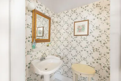 A small bathroom with a white sink and floral wallpaper.
