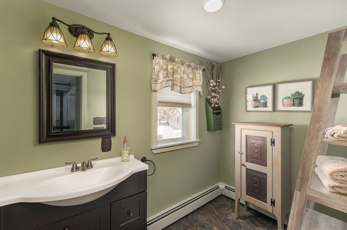 A modern bathroom with a white sink and dark cabinets, featuring a mirror above the counter.