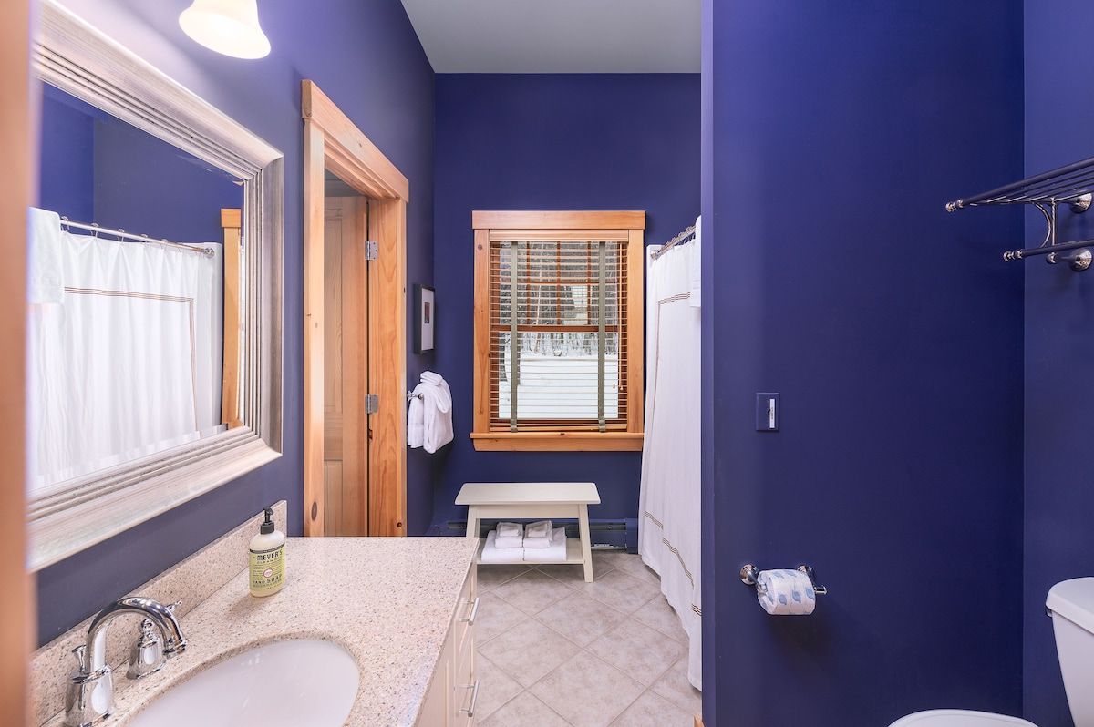 A clean and well-appointed bathroom with a large mirror, sink, and toilet.