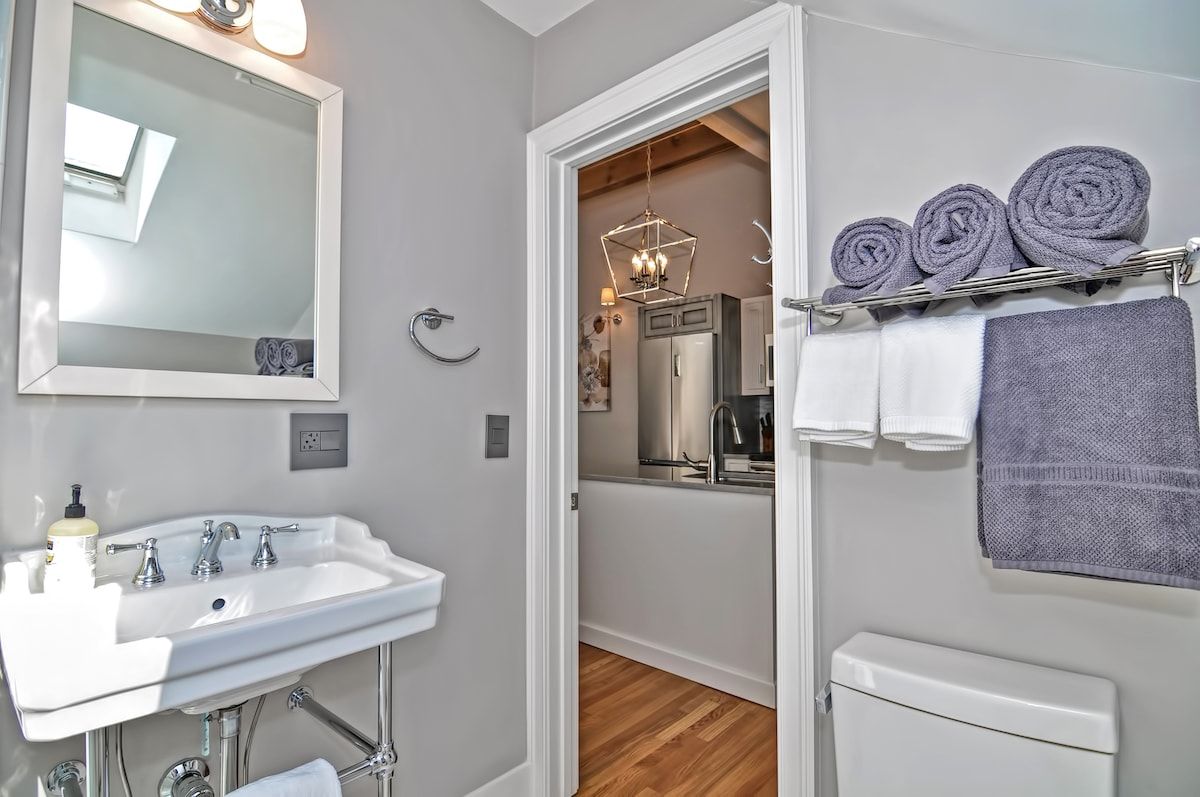 A clean and modern bathroom with a white sink, mirror, and towels.