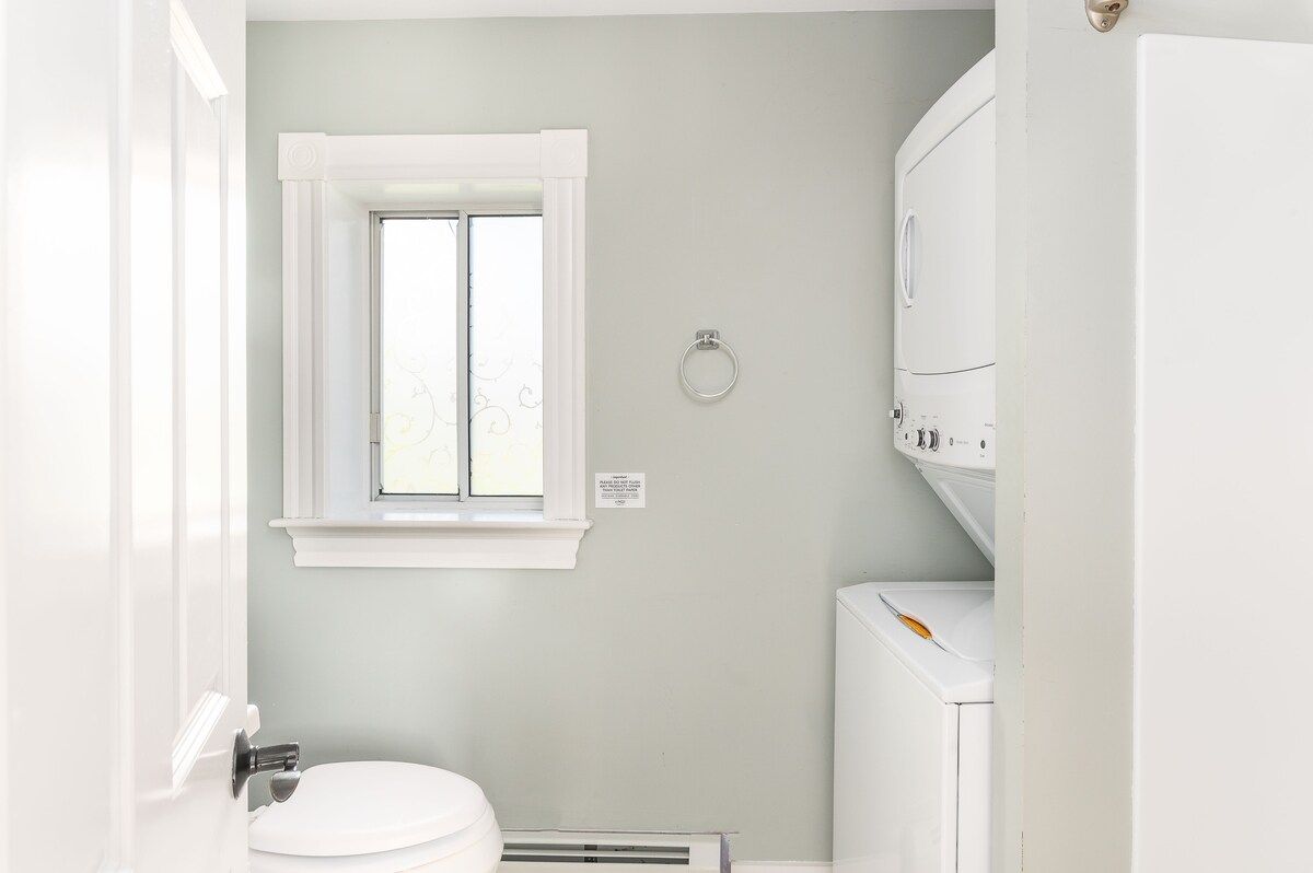 A clean and modern bathroom with a window, toilet, and washing machine