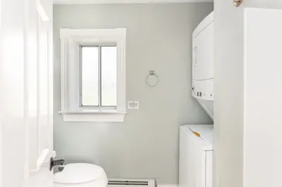 A clean and modern bathroom with a window, toilet, and washing machine