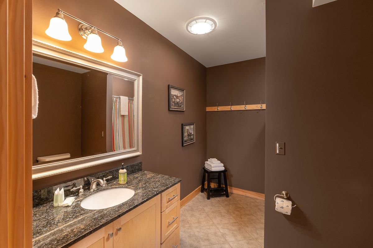 A modern bathroom with a large mirror, granite countertop, and a white sink.