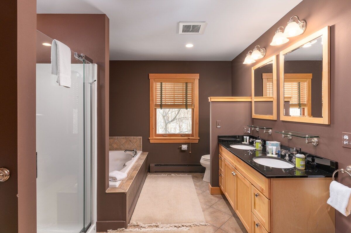 A modern bathroom with a bathtub, double sink vanity, and large mirror.