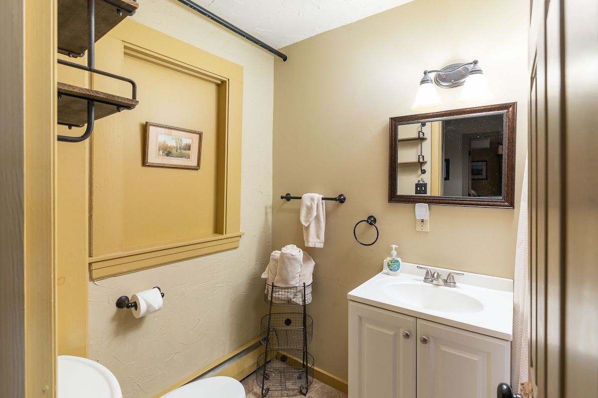 A clean and well-appointed bathroom with a white sink, mirror, and toilet.