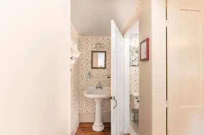 A small bathroom with a pedestal sink and floral wallpaper