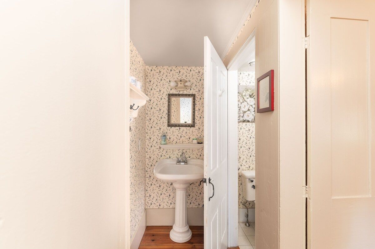 A small bathroom with a pedestal sink and floral wallpaper