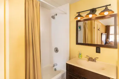 A clean and well-lit bathroom with a bathtub, shower, and sink.