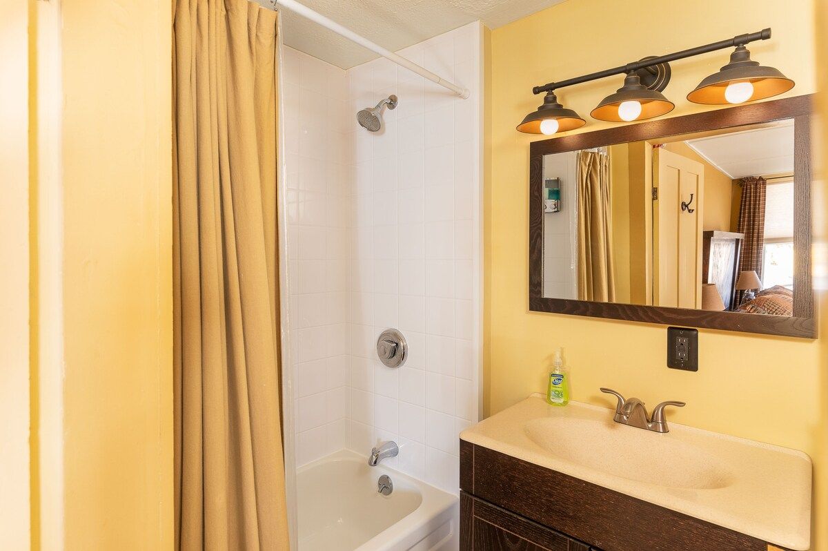 A clean and well-lit bathroom with a bathtub, shower, and sink.