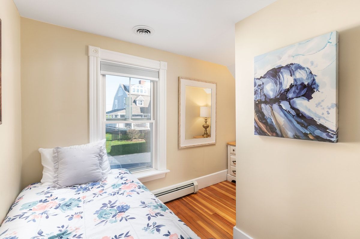 Cozy bedroom with a floral comforter and a window overlooking the neighborhood.