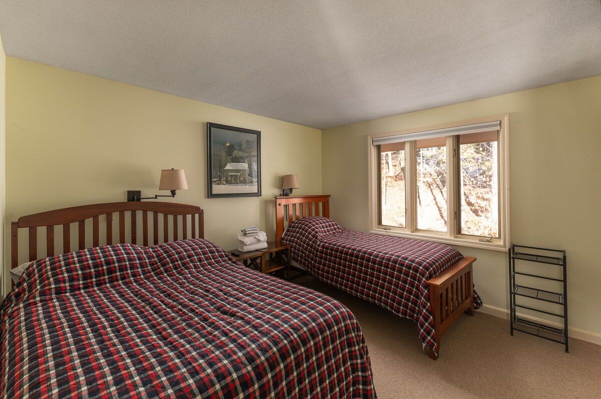 Cozy bedroom with two twin beds and a window overlooking the woods