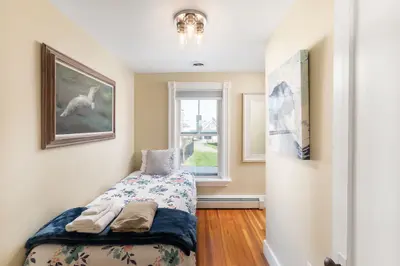 Cozy single bed with floral bedding and a window overlooking the neighborhood