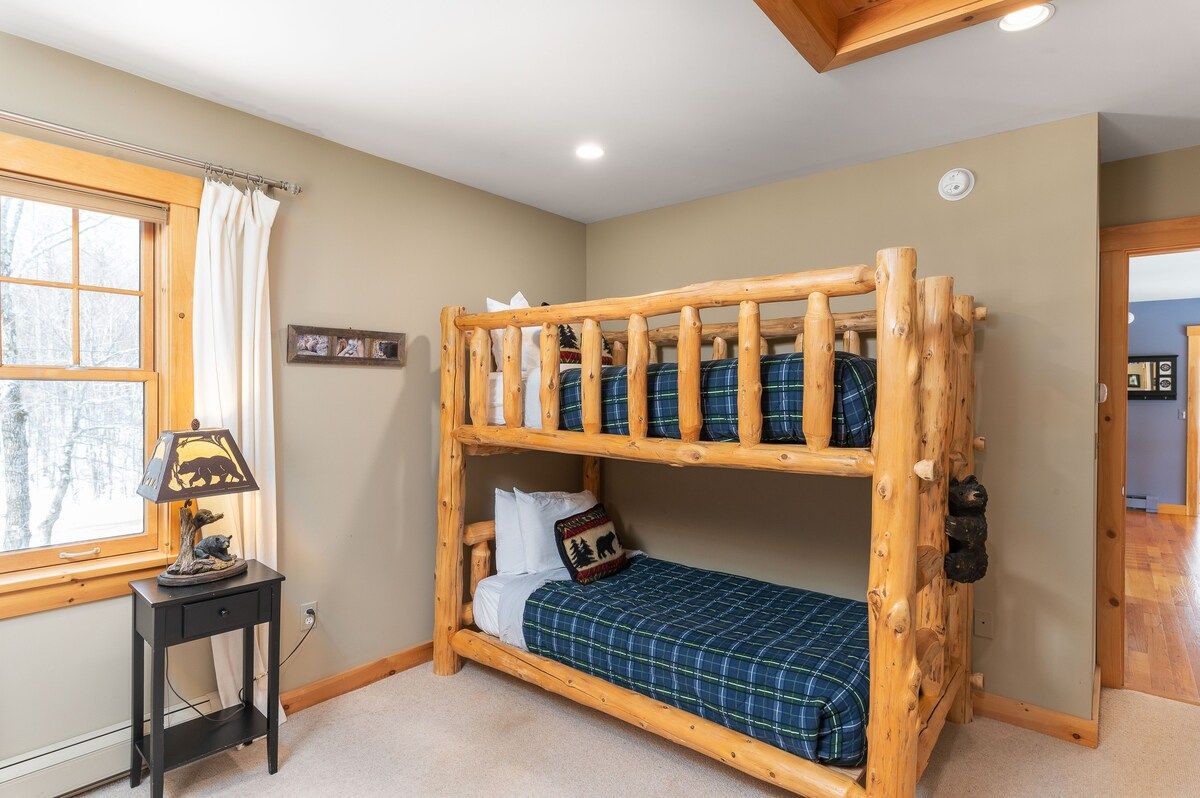 Cozy bunk room with a rustic wooden bed and mountain views through the window