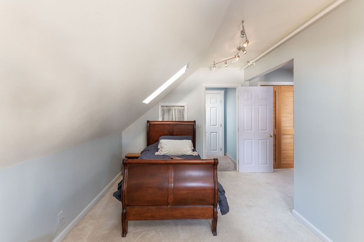 Spacious master bedroom with a dark wood sleigh bed and white carpet