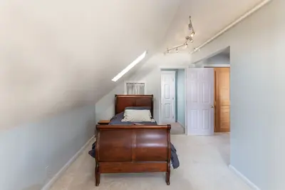 Spacious master bedroom with a dark wood sleigh bed and white carpet