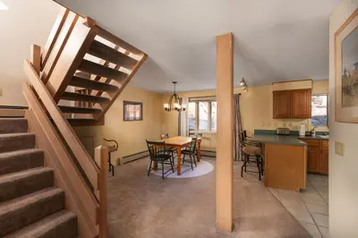 A cozy dining area with a wooden table and chairs, surrounded by warm lighting and natural light from the windows.