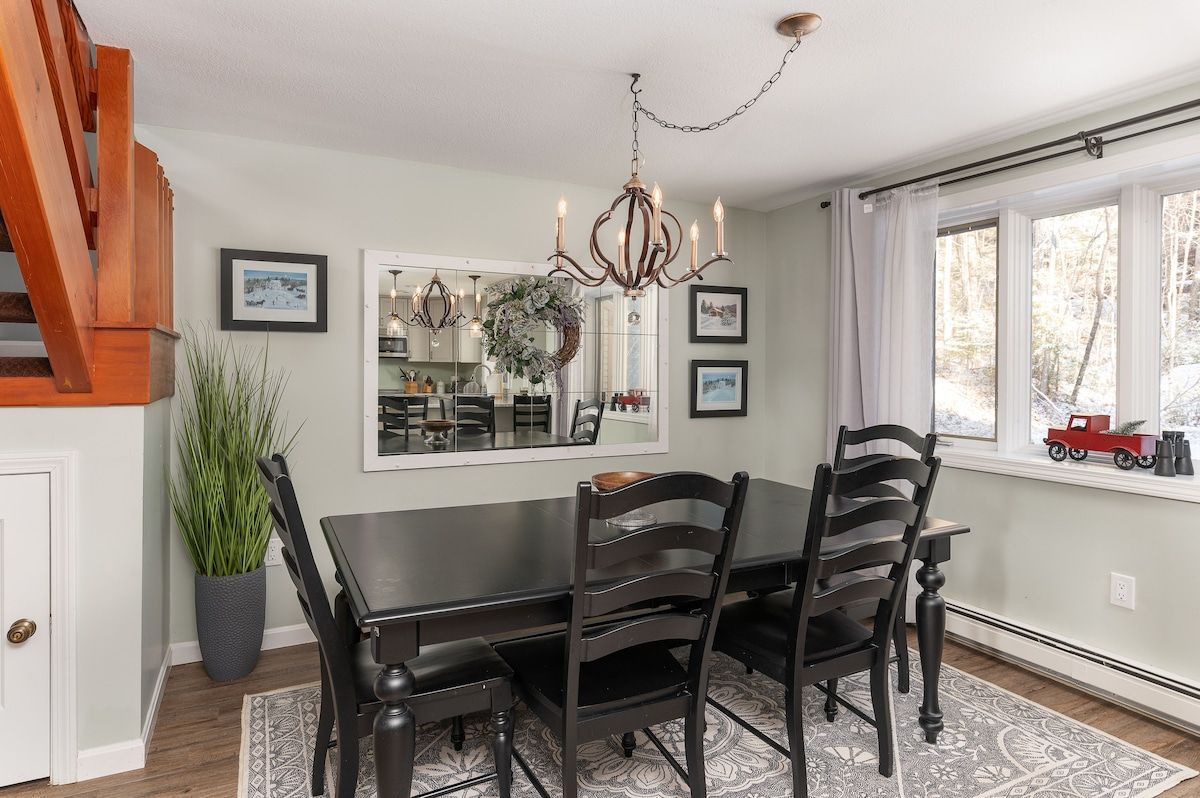 A cozy dining area with a dark wood table and chairs, surrounded by a mirror and framed artwork.