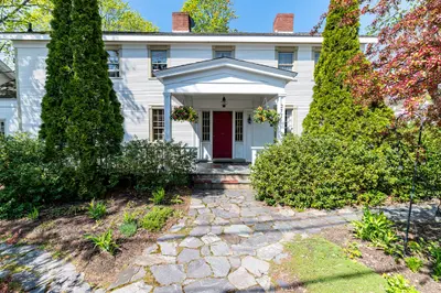 A large white house with a red door and a stone walkway