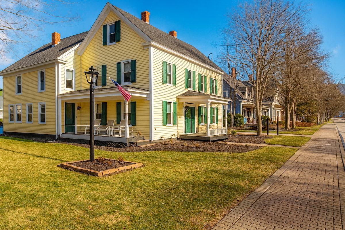 A large yellow house with a covered porch and an American flag