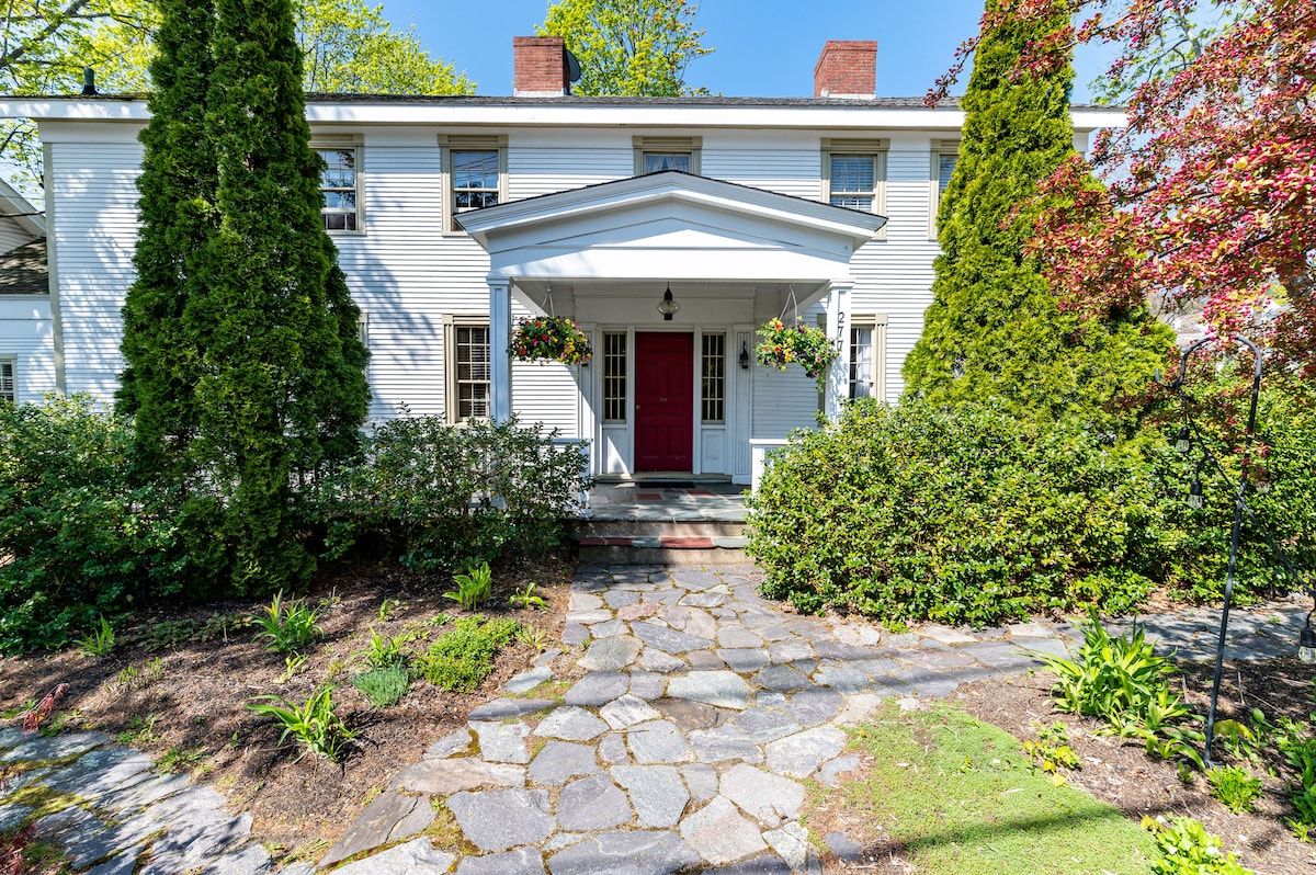 A large white house with a red door and a stone walkway