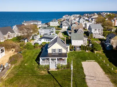 Aerial view of a beachfront house with a large yard and ocean views.