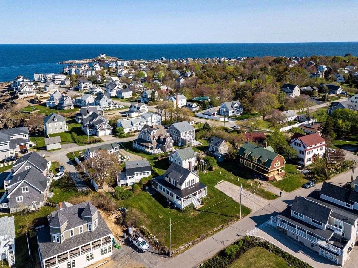 Aerial view of a coastal neighborhood with houses and trees, overlooking the ocean