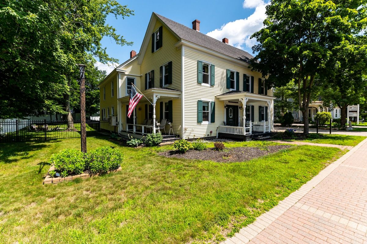 A large yellow house with a front porch and an American flag