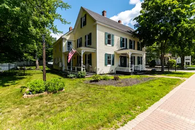 A large yellow house with a front porch and an American flag