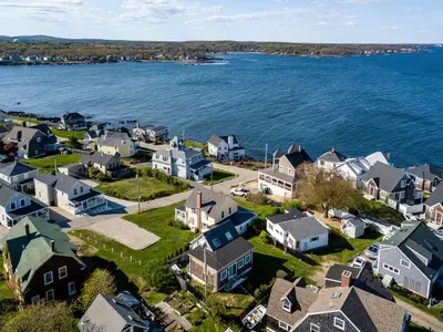 Aerial view of a coastal neighborhood with houses and the ocean in the background.