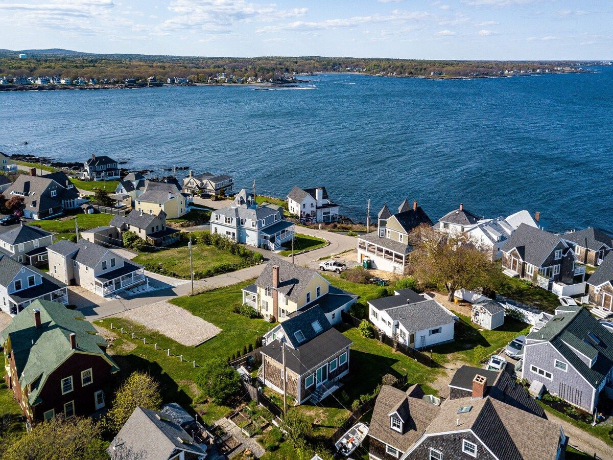 Aerial view of a coastal neighborhood with houses and the ocean in the background.