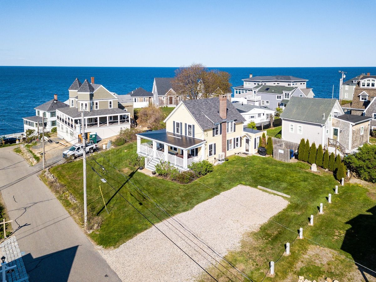 Aerial view of a beachfront house with a large yard and ocean views.