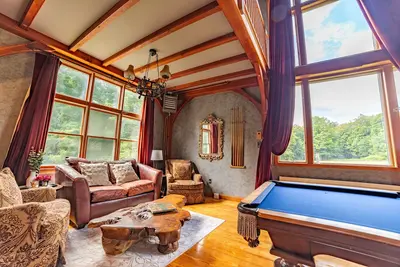 Cozy game room with pool table and large windows overlooking the forest