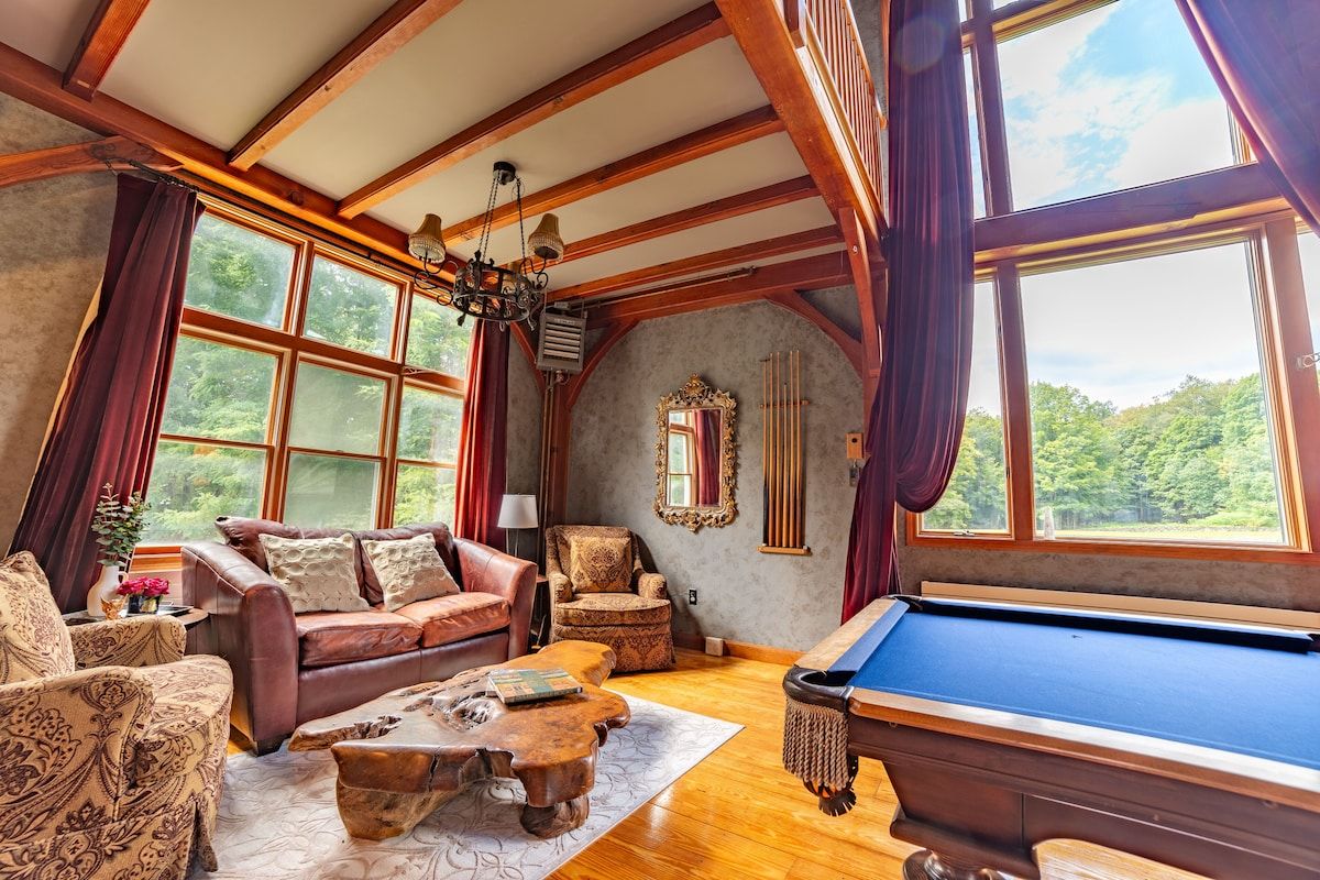 Cozy game room with pool table and large windows overlooking the forest
