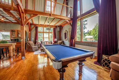 A spacious game room with a pool table and large windows offering a view of the surrounding area.