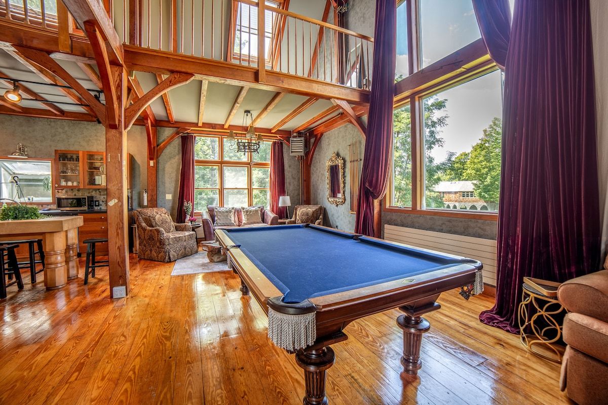 A spacious game room with a pool table and large windows offering a view of the surrounding area.