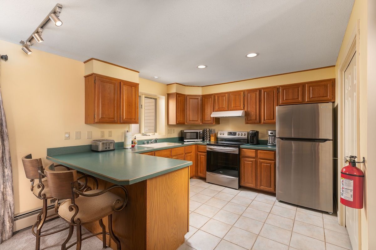 A well-equipped kitchen with stainless steel appliances and a green countertop.