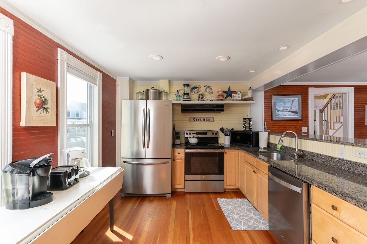 A well-equipped kitchen with stainless steel appliances and granite countertops, featuring a large refrigerator, oven, and sink.