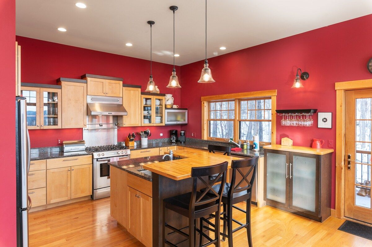 A modern kitchen with stainless steel appliances and a large island, featuring a sink and bar stools.