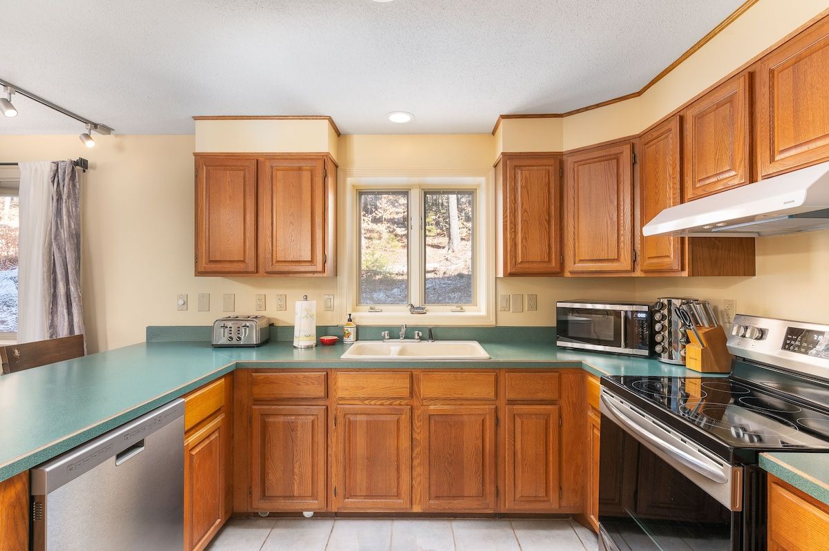 A well-equipped kitchen with stainless steel appliances and wooden cabinets, featuring a sink, stove, microwave, and dishwasher.