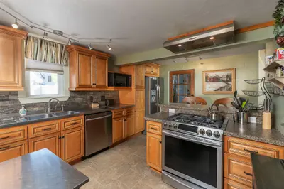 A well-equipped kitchen with stainless steel appliances and granite countertops, featuring a range, refrigerator, sink, and microwave.