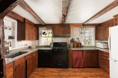 A rustic kitchen with dark wood cabinets and granite countertops, featuring a black stove and white refrigerator.
