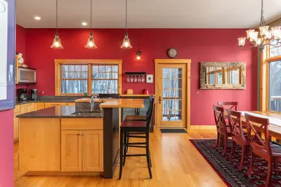 A spacious kitchen with a large island, wooden cabinets, and a dining area with a table and chairs.