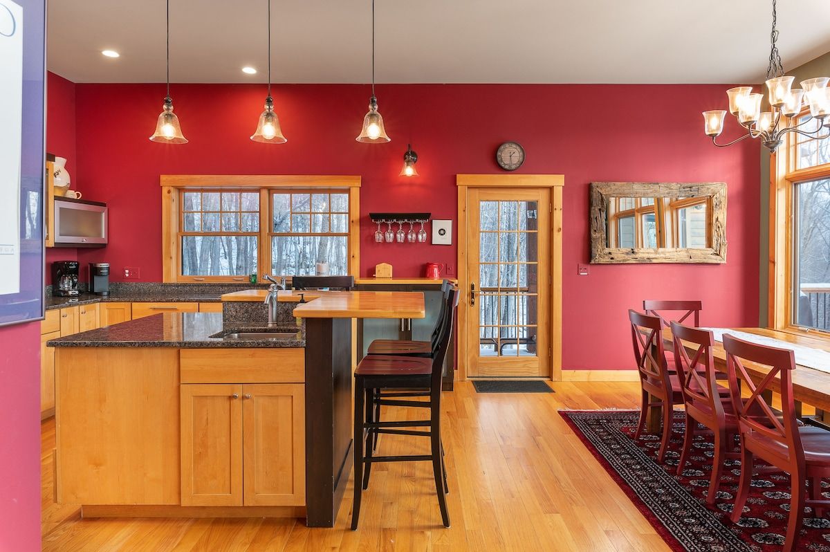 A spacious kitchen with a large island, wooden cabinets, and a dining area with a table and chairs.