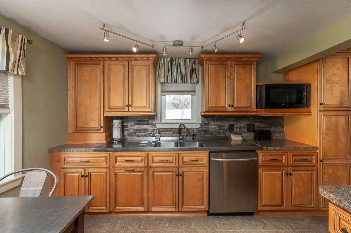 A well-equipped kitchen with stainless steel appliances and granite countertops, featuring a sink, dishwasher, and microwave.