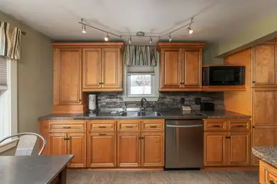 A well-equipped kitchen with stainless steel appliances and granite countertops, featuring a sink, dishwasher, and microwave.