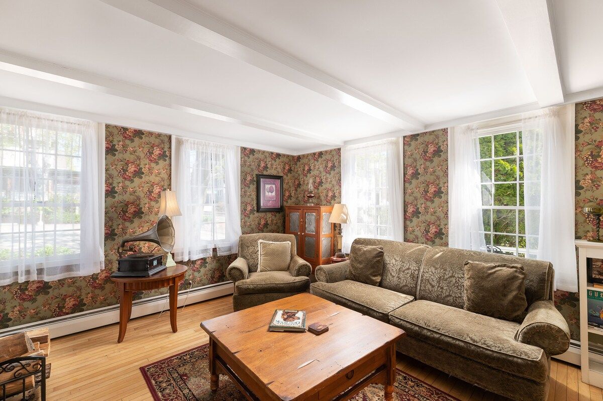 Cozy living room with floral wallpaper, comfortable sofa and armchair, and a vintage gramophone